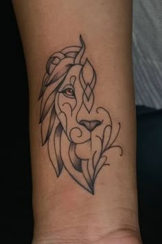 a tattoo on the wrist of a woman with a lion's head and leaves