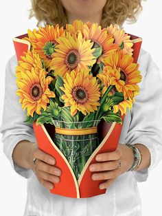 a woman is holding a bouquet of sunflowers in a vase with an open book