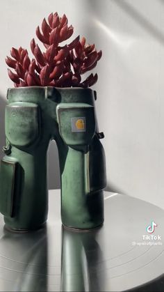 two green vases with red flowers in them