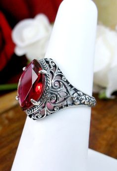 Simulated Red Ruby Ring Iris Design #201 Custom Made This is a stunning Art Deco/Edwardian reproduction in sterling silver filigree with a 4ct simulated ruby gemstone. The flawless gem is 13mm in long by 8mm wide. The ring is 16mm North to South on the finger. The inside of the band is marked 925 for sterling silver. Notice the beautiful craftsmanship of the silver filigree floral setting. This is an ornate and detailed ring. This is a lovely reproduction of an antique filigree ring, and it is r Red Heirloom Jewelry, Vintage Red Rings For Valentine's Day, Fine Jewelry Red Ruby Ring With Intricate Design, Elegant Red Crystal Ring With Stone Setting, Red Crystal Ring With Stone Setting For Anniversary, Elegant Red Oval Ruby Jewelry, Red Gemstone Accented Anniversary Rings, Red Rings With Gemstone Accents For Anniversary, Formal Red Crystal Ring Fine Jewelry