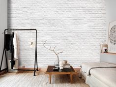 a white brick wall in a bedroom next to a bed and table with a vase on it