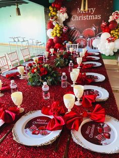 the table is set for christmas dinner with red and white plates, silverware and candy