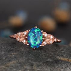 an opal and diamond ring sitting on top of a rock