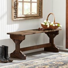 a wooden bench sitting in front of a mirror next to a boot and flower arrangement