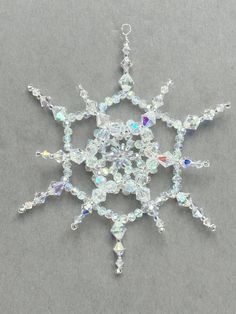 a snowflake made out of crystal beads on a gray surface with white background