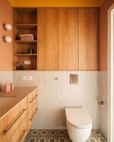 a bathroom with wooden cabinets and a toilet in the middle, along with tile flooring