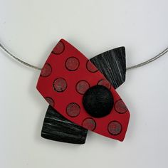 a red and black piece of art hanging from a string