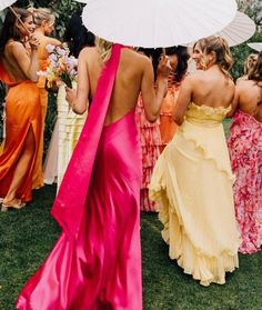 a group of women standing around each other holding umbrellas in their hands and wearing dresses