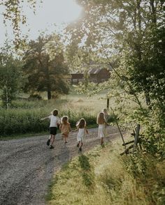 three children walking down a dirt road holding hands