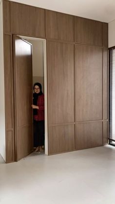 a woman is standing in the doorway of an empty room with wood paneling on the walls