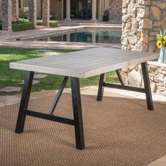 a table sitting on top of a brown rug next to a pool and stone building