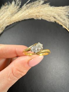 a hand holding two gold rings with one diamond