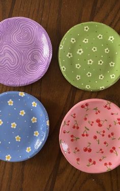 four colorful plates sitting on top of a wooden table