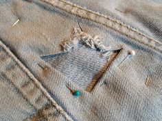 an old pair of jeans with holes in the back pocket and some pins sticking out of them