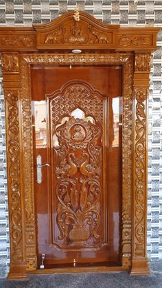 an ornate wooden door in front of a brick wall