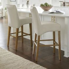 two white bar stools in front of a kitchen island