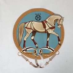 a white and gold plate with a horse painted on it's side, hanging from the wall