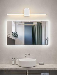 a bathroom with a sink, mirror and lights on the wall above it's counter