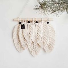 three white macrame wall hangings with black beads and wooden sticks on them