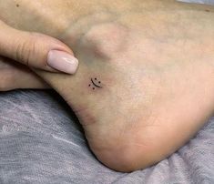 a woman's foot with a small smiley face tattoo on the left side of her toe