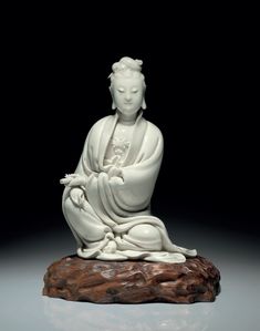 a white buddha statue sitting on top of a wooden stump