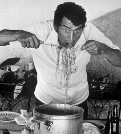 a man is eating spaghetti from a large pot on the table in front of him