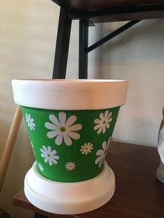 a green flower pot sitting on top of a wooden table