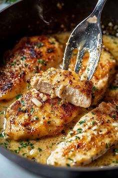 a close up of chicken in a skillet with a fork