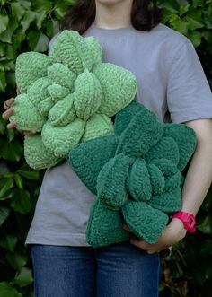 a woman holding two pieces of green crocheted items in front of her face