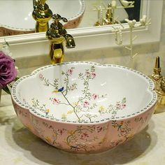 a pink and white bowl sink sitting on top of a counter next to a mirror