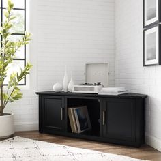 a black entertainment center in a white living room with books and magazines on it's shelf