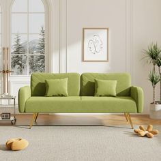 a green couch sitting on top of a rug in a living room next to a window