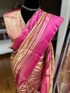 Indulge in ethereal elegance with our exquisite Kora Tissue Silk Saree, featuring a luxurious Katan Silk border adorned with shimmering gold zari. This masterpiece combines the delicate transparency of Kora tissue with the rich texture of Katan silk, creating a captivating contrast. The saree's ethereal beauty is further enhanced by the intricate gold zari work on the border, adding a touch of opulence. Perfect for weddings, cocktail parties, or any special occasion where you desire to make a lasting impression, this saree is a must-have for the discerning woman. Fabric: Kora by Tissue Silk Saree with Katan Silk Border Color: Rose Gold Embellishments: Gold Zari Occasion: Weddings, Parties, Festive Photos don't do justice .. this saree is just... glamorous Comes with fall/ Pico / tassels an Gold Handloom Pre-draped Saree For Wedding, Elegant Chanderi Pre-draped Saree For Celebration, Festive Fusion Silk Pre-draped Saree, Elegant Slub Silk Blouse Piece, Elegant Slub Silk Blouse Piece With Traditional Drape, Elegant Gold Pre-draped Saree For Festivals, Transitional Gold Chanderi Pre-draped Saree, Elegant Slub Silk Pre-draped Saree With Zari Work, Gold Pre-draped Chanderi Saree With Sheer Dupatta