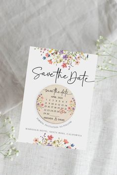 save the date magnets with flowers on them sitting on top of a white sheet