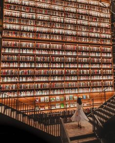 a woman is walking up some stairs in front of a book shelf filled with books