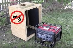 a portable generator sitting in the grass next to a wooden box with a no sound sign on it