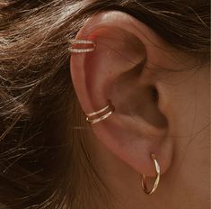 a woman's ear with two thin gold hoops