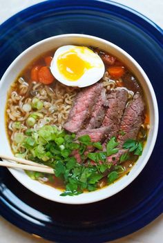 a bowl of soup with meat, noodles and an egg on the top is ready to be eaten