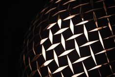 a close up view of an object made out of metal mesh and wood sticks, with the light shining on it