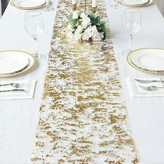 the table is set with white and gold place settings