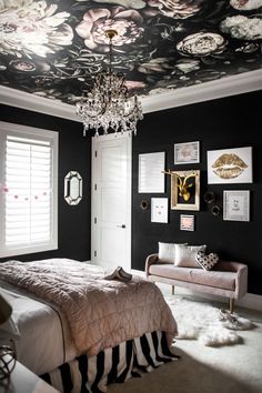 a bedroom decorated in black and white with flowers painted on the ceiling, chandelier