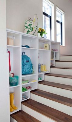 a white book shelf filled with lots of books next to a stair case full of colorful items