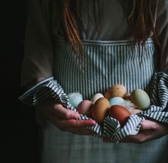 a woman holding an assortment of eggs in her hands