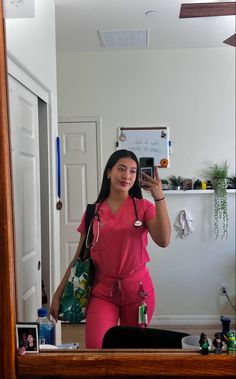 a woman in pink scrubs taking a selfie