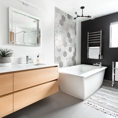 a white bath tub sitting next to a sink under a bathroom mirror on top of a wooden cabinet