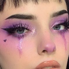 a close up of a woman with purple makeup and hearts on her cheek, looking at the camera