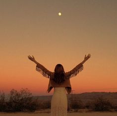 a woman standing in the desert with her arms outstretched