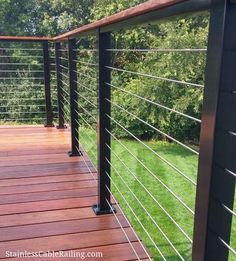 a wooden deck with metal railings and green grass in the backgroung