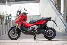 a red and black motorcycle parked in front of a building