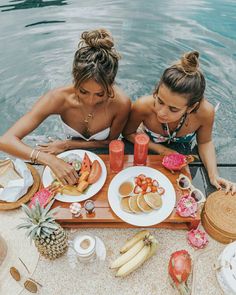 two women sitting at a table with food on it